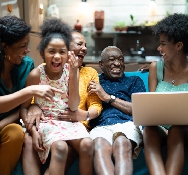 Family together laughing on a couch with a laptop
